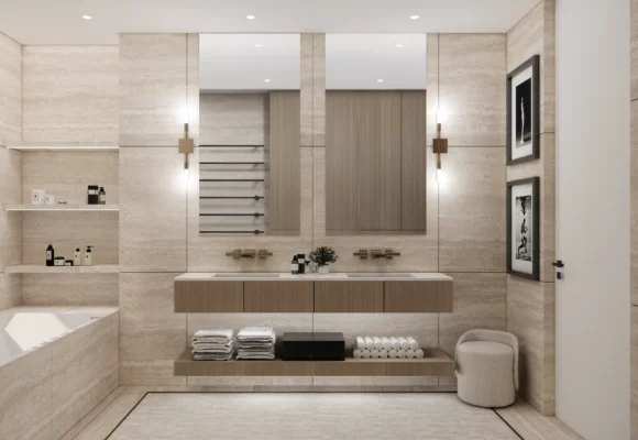 Główna ściana z podwójną umywalką i dużymi lustrami tworzy harmonijną kompozycję, w której ciepłe odcienie kamienia i drewna łączą się z eleganckim oświetleniem. Pod umywalką zaprojektowano półkę na ręczniki, co zwiększa funkcjonalność przestrzeni, zachowując jej estetykę.